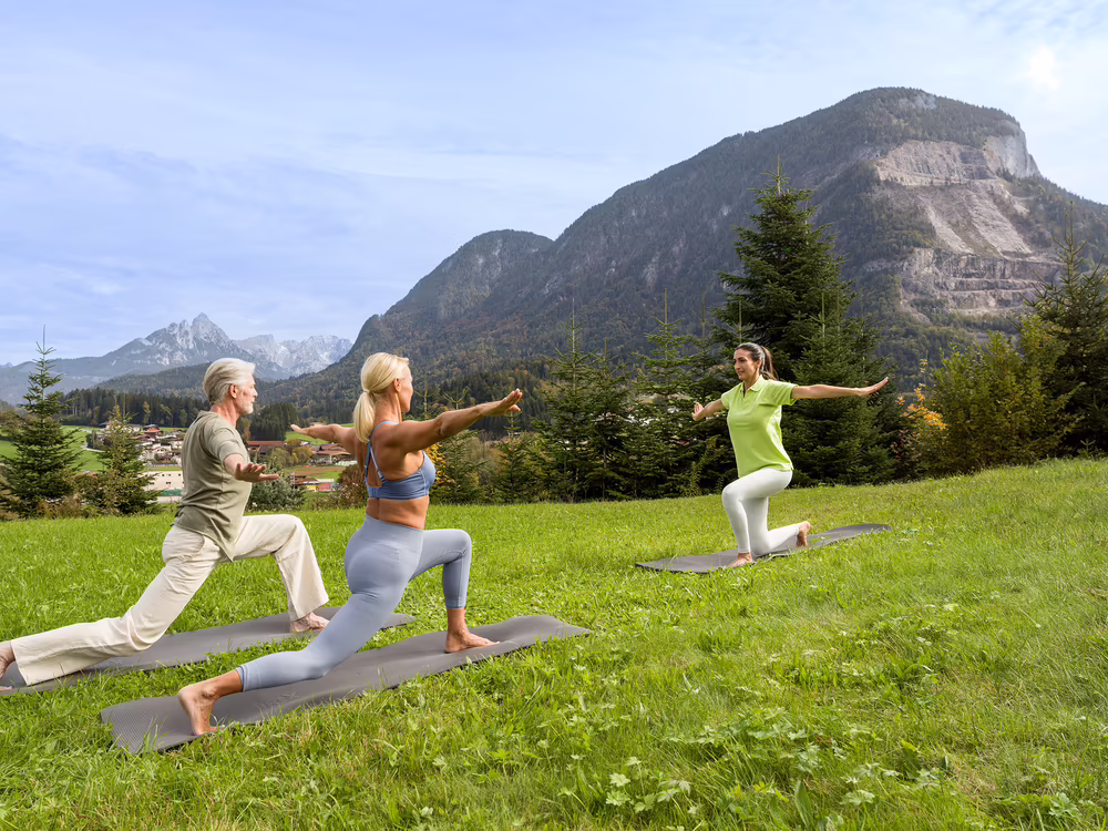 Zwei Personen machen Yoga im Freien vor dem Hotel DAS SIEBEN