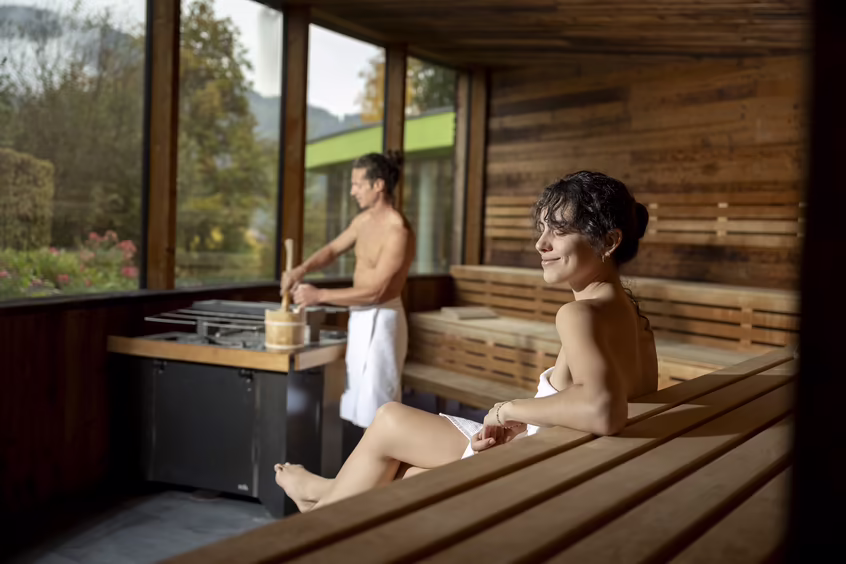 Zwei Personen sitzen entspannt der Panoramasauna im Adults Only Wellnesshotel DAS SIEBEN in Tirol