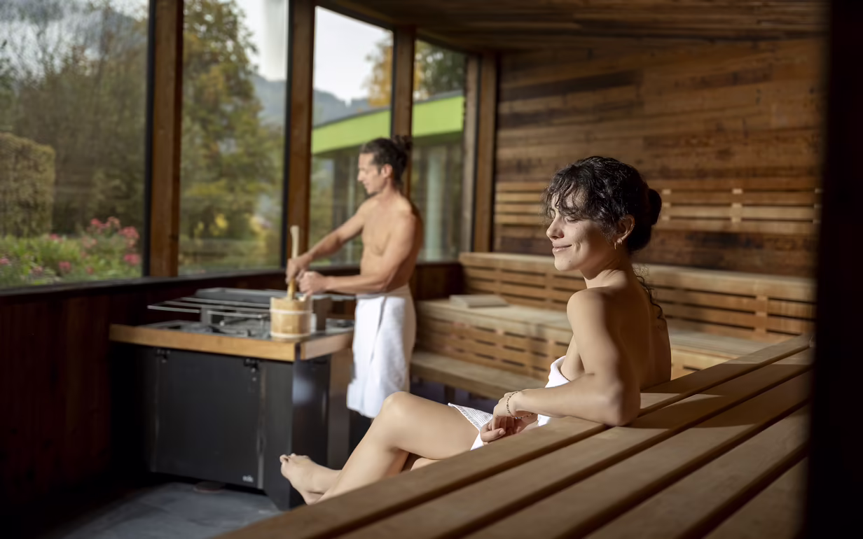 Zwei Personen sitzen entspannt der Panoramasauna im Adults Only Wellnesshotel DAS SIEBEN in Tirol