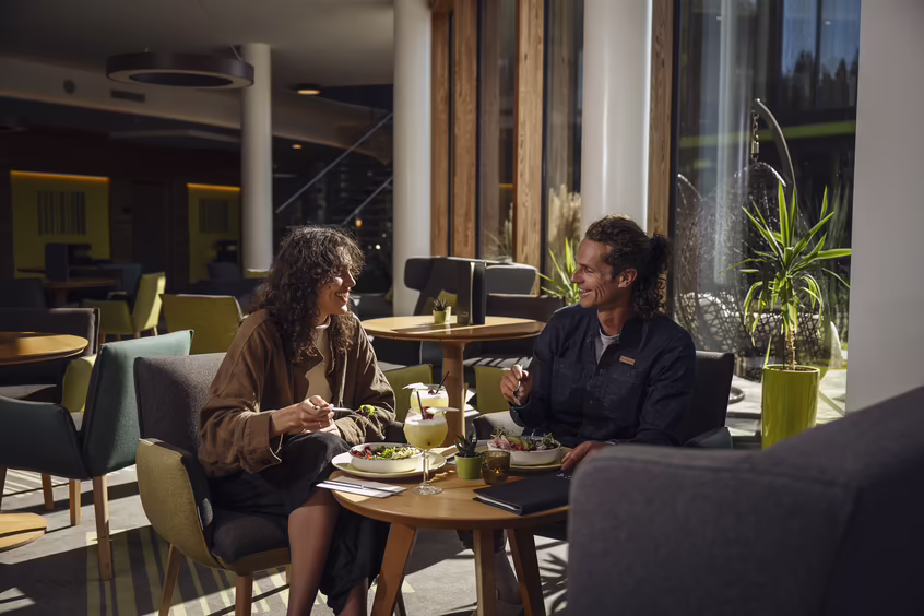 Zwei Personen sitzen im Restaurantbereich von DAS SIEBEN und essen gemeinsam