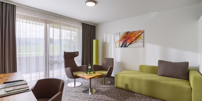 Sitzgruppe mit Sofa und Tisch in modernem Hotelzimmer
