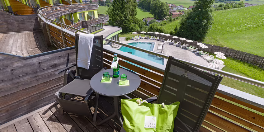Balkon mit Tisch und Stühlen sowie Blick auf Pool und Natur