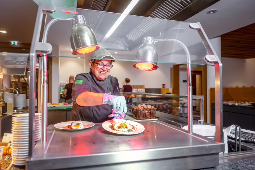 Köchin richtet Speisen an einer Station im Hotel DAS SIEBEN an