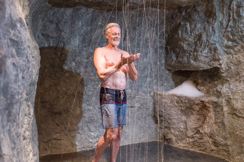 Mann steht unter einer Dusche im Spa Bereich im DAS SIEBEN