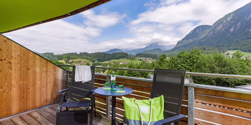 Doppelzimmer mit Holzbett, grüner Wand und großem Fenster zum Balkon