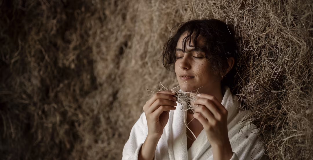 Frau im Bademantel riecht an Heu in einem Ruheraum bei DAS SIEBEN