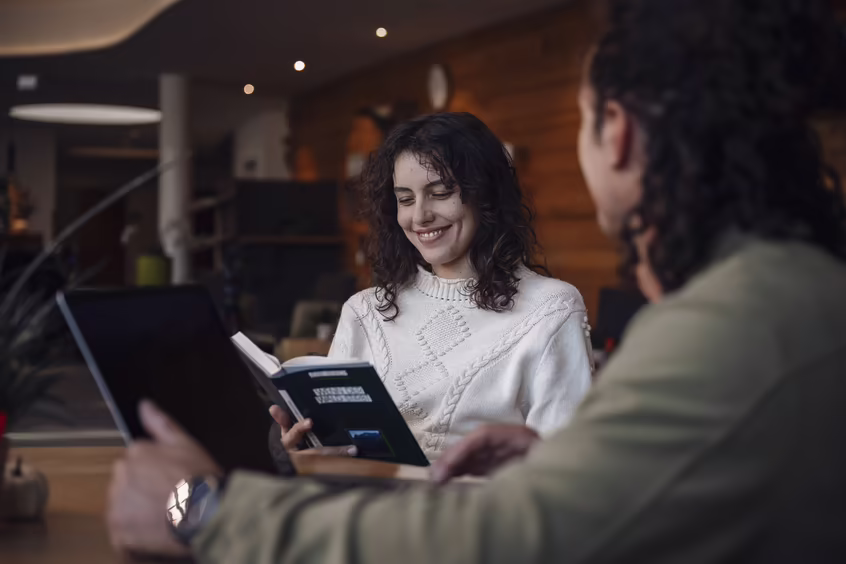 Zwei Personen in der Lounge des DAS SIEBEN, eine liest, die andere arbeitet am Laptop