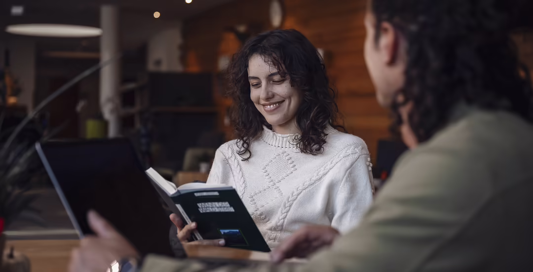 Zwei Personen in der Lounge des DAS SIEBEN, eine liest, die andere arbeitet am Laptop