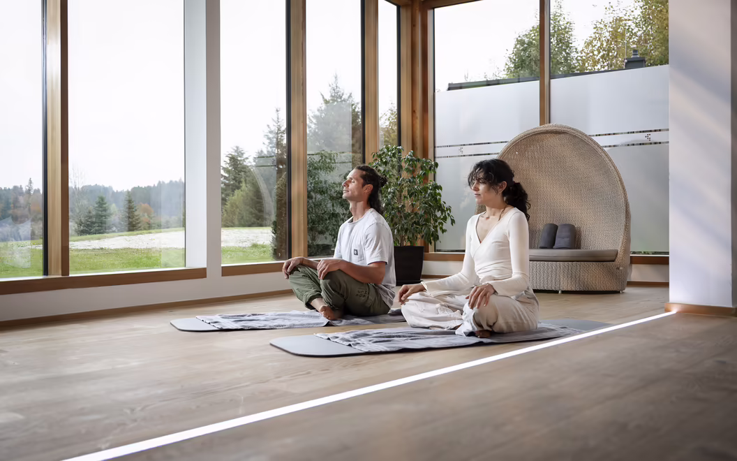 Zwei Personen sitzen auf Yogamatten in einem hellen Raum im DAS SIEBEN