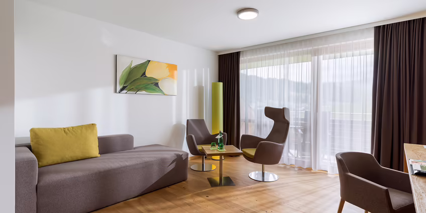 Heller Wohnbereich mit Sofa, Sesseln und großen Fenstern