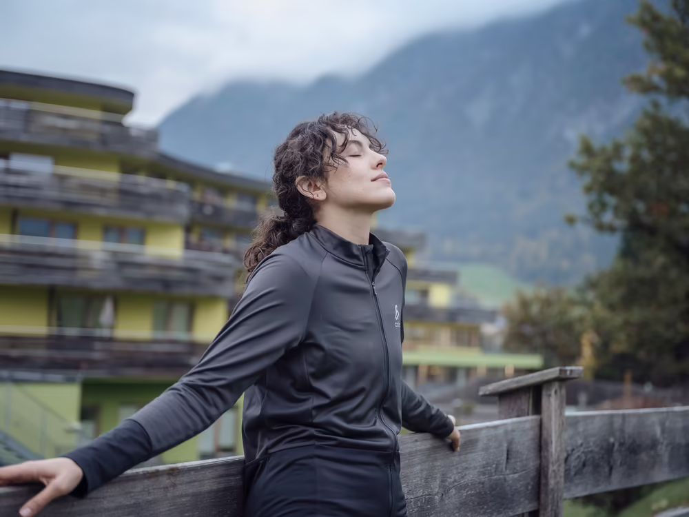 Frau steht am Holzzaun mit Blick auf DAS SIEBEN und die umliegenden Berge